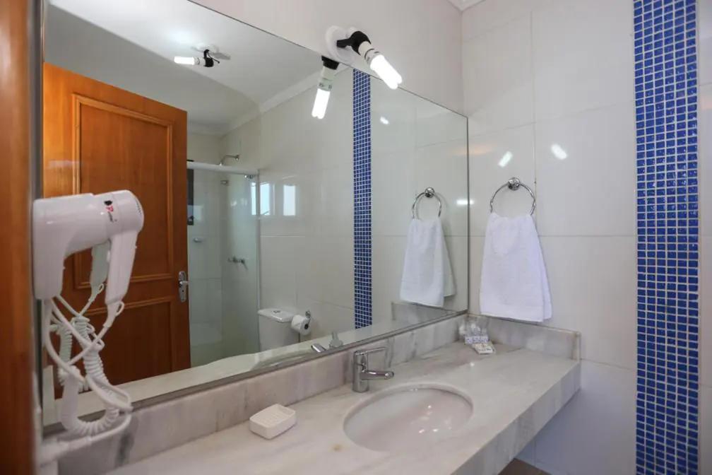 Banheiro privativo de quarto com box de vidro e bancada de mármore, Pousada Praia do Meio, Torres