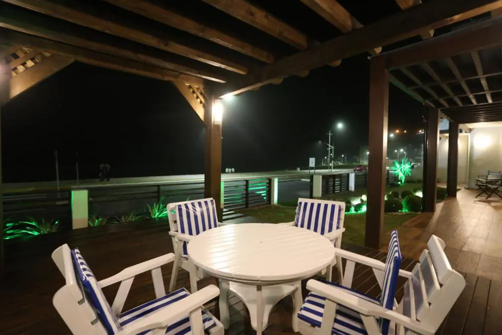 Deck de madeira com cadeiras azuis e brancas à noite na Pousada Praia do Meio, Prainha, Torres
