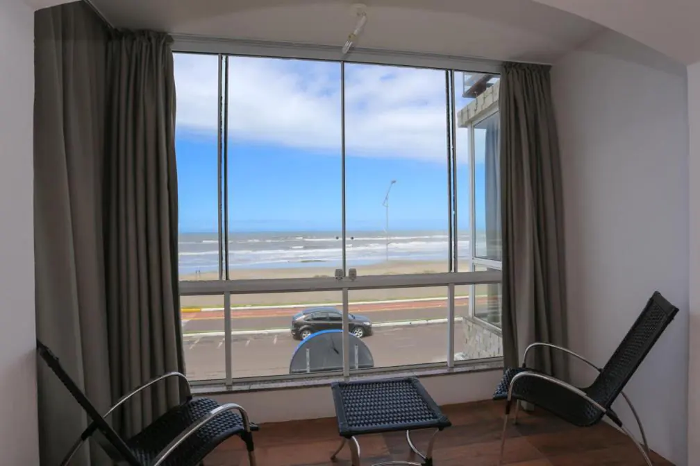 Quarto com janelão do chão ao teto e vista do mar da Prainha, em Torres
