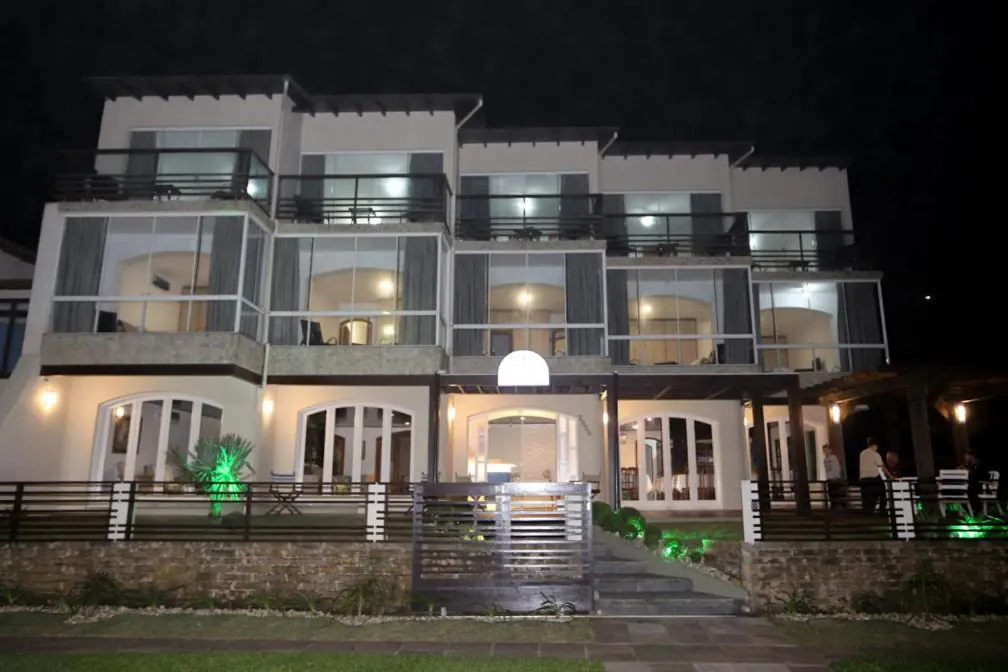 Fachada iluminada da Pousada Praia do Meio à noite, na Prainha, Torres