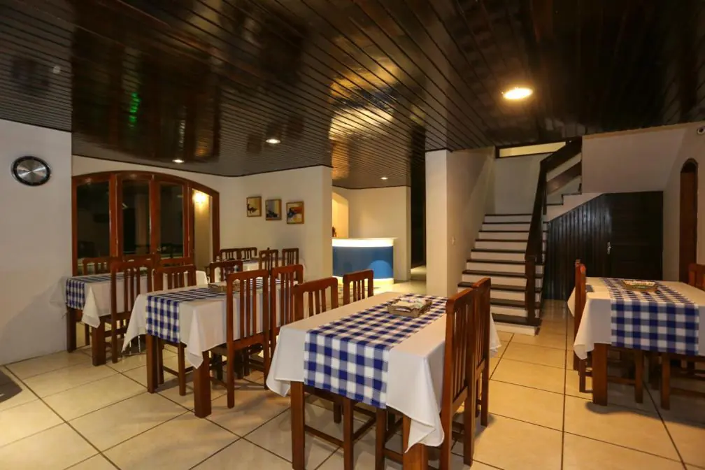 Salão do café da manhã com mesas de toalha xadrez na Pousada Praia do Meio, Torres